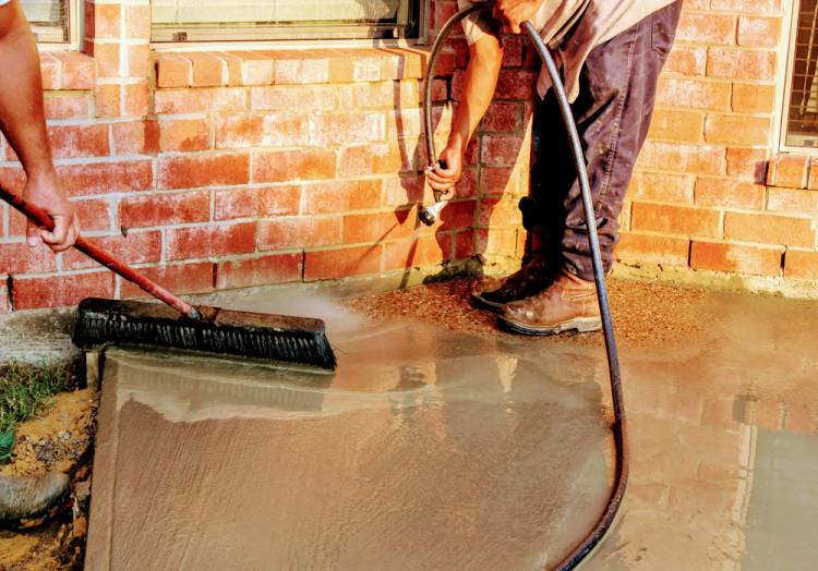 Worker Giving Finishing Touch To Exposed Aggregate Concrete By Washing