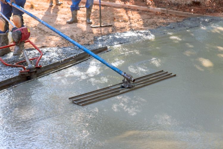 Construction Worker Smoothing Concrete With Screed